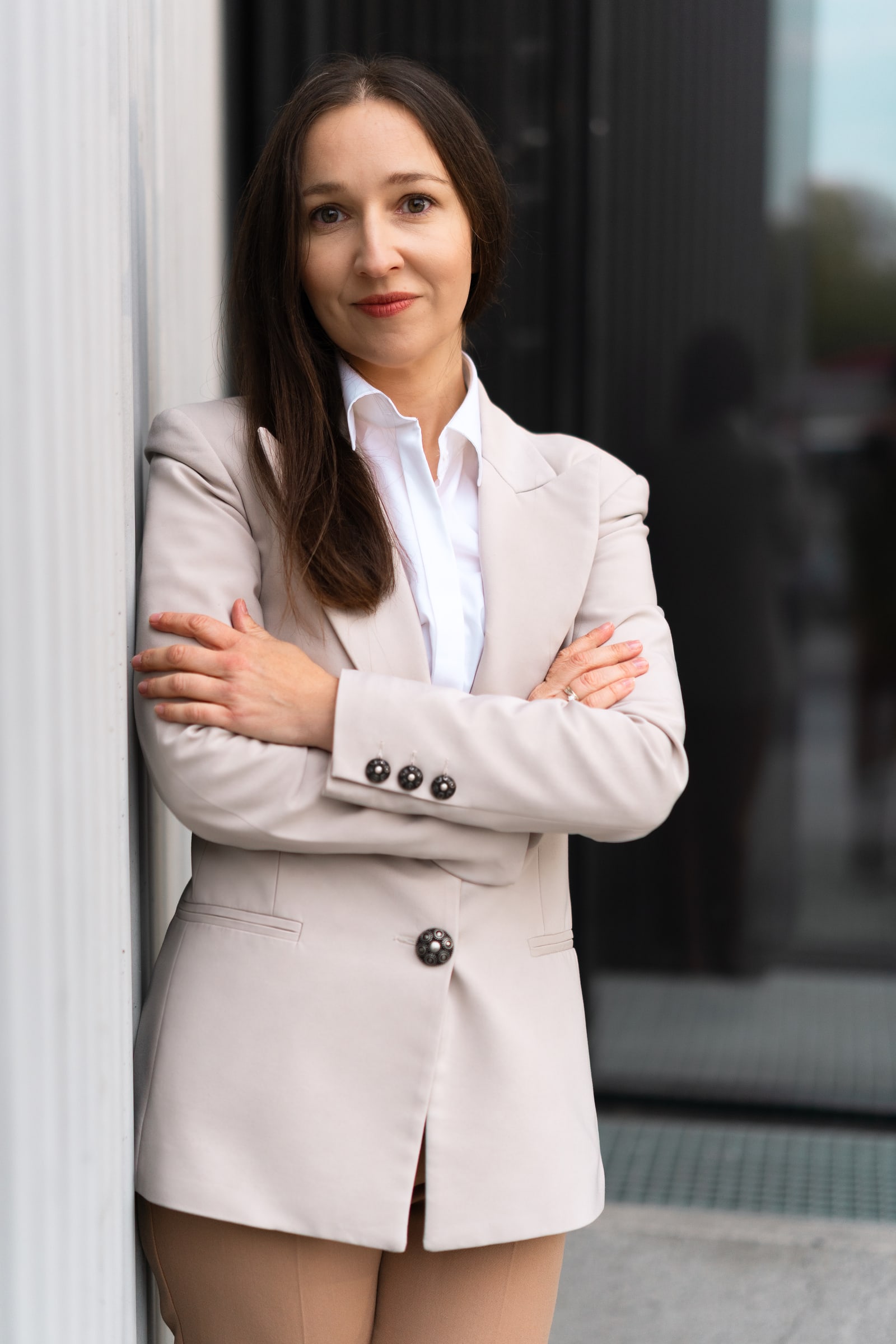 Portret Joanny Legun w jasnej marynarce przy fasadzie budynku